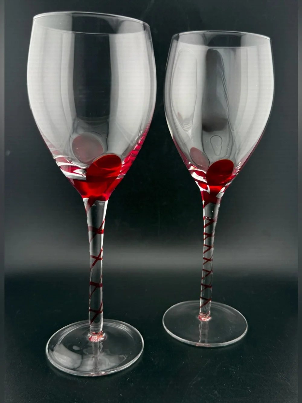 2 Pier 1, red ribbon swirl stem wine glasses, w/ a red swirl design on the stem.